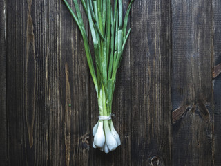 flat lay bunch of green onion on a dark wooden surface