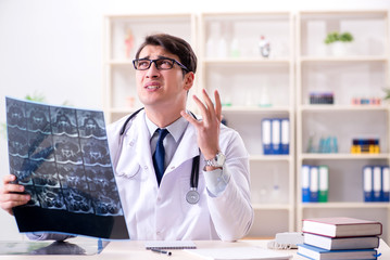 Young doctor looking at x-ray images in clinic