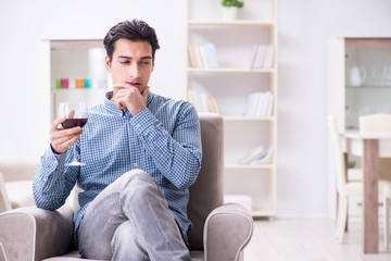 Young man drinking wine at home