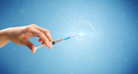 Female doctor hand holding syringe with blue background and shine