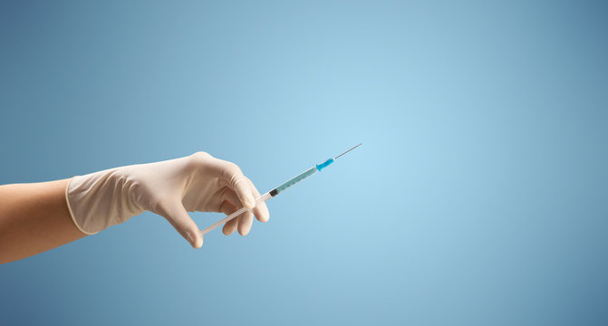Female doctor hand holding syringe with blue background
