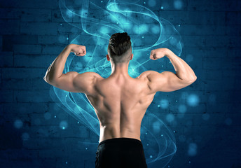 Fototapeta na wymiar A sexy body builder lifting weight and showing his muscular, hot body in front of a blue urban brick wall with drawn light beams concept