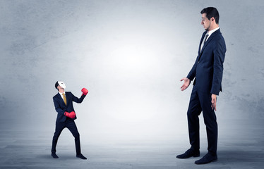 Fototapeta premium Big businessman being afraid of small masked businessman with box gloves in an empty room concept 