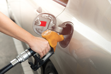 Closeup of man pumping gasoline fuel in car at gas station. Fuel nozzle with hose in hand