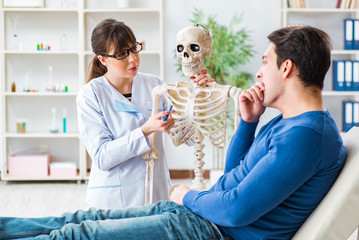 Doctor showing type of injury on skeleton to patient