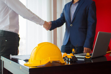 Asian engineer shaking hands with the business customer , finishing up a meeting , focus on yellow helmet