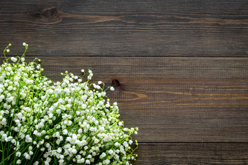 Lily of the valley flowers frame. Spring background on dark wooden desk top view copy space