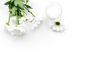 Natural emollient chamomile cream. White cream in small jar near chamomile flowers on white background top view copy space