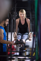 woman working out with personal trainer on gymnastic rings