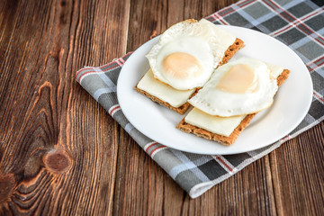 Healthy sandwiches with soft cheese and egg on crisp rye bread on dark wooden background. Breakfast or snack.