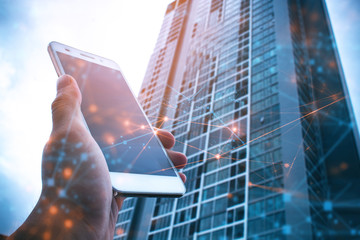 hand with phone mobile and building in network background with business concept, application on...
