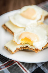Obraz na płótnie Canvas Healthy sandwiches with soft cheese and egg on crisp rye bread on dark wooden background. Breakfast or snack.