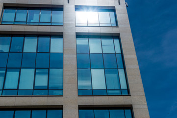 Modern office building in minimalism style with reflection of sunlight and against a blue sky background