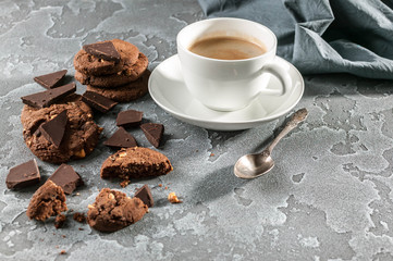 Chocolate biscuits and a cup of coffee on a gray concrete background.