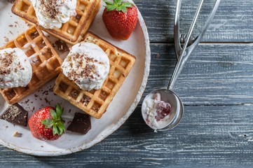 Belgian Wafers with vanilla ice cream, fresh strawberries and chocolate. Delicious breakfast. Top view