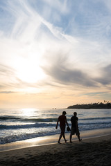 Male friends walking side by side in silhouette on beach