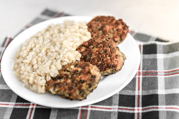 Chicken mushroom cutlets and pearl porridge on white plate on light background. Healthy dinner.
