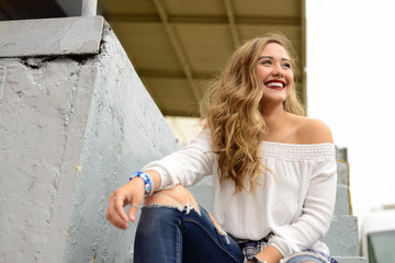 Beautiful girl with white shirt and side braids sitting on urban stairs