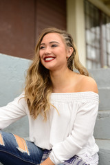 Beautiful girl with white shirt and side braids sitting on urban stairs