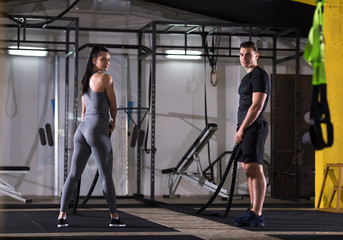 Obraz na płótnie Canvas sports couple doing battle ropes cross fitness exercise