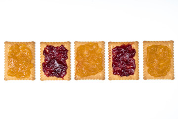 Some dry biscuits with jam on a white surface