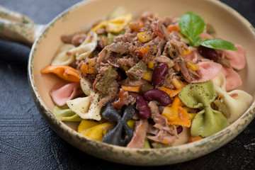 Farfalle pasta with tuna fillet, red beans and corn in a serving pan, selective focus, close-up