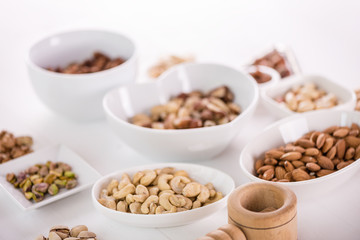 variety, mixture of different nuts on white background in white bowls 