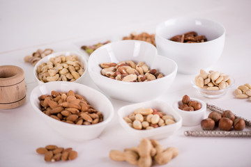 variety, mixture of different nuts on white background in white bowls 