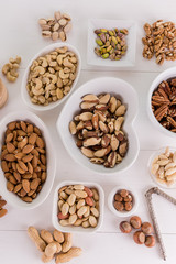 variety, mixture of different nuts on white background in white bowls 