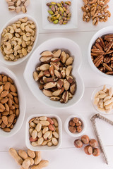 variety, mixture of different nuts on white background in white bowls 