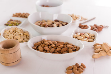 variety, mixture of different nuts on white background in white bowls 