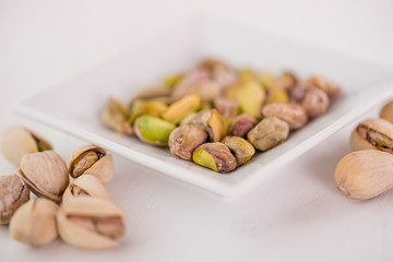 pistachio nuts in white dish on white background