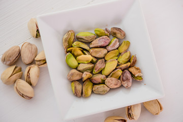 pistachio nuts in white dish on white background