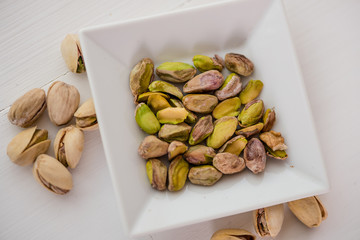 pistachio nuts in white dish on white background