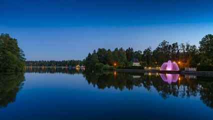 Obraz premium Fountain with illumination on the shore of the evening lake