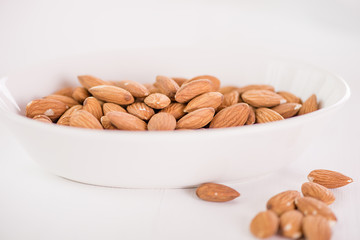 heap of almonds in white dish on white background 