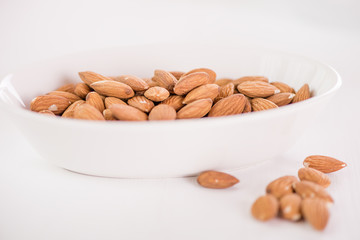heap of almonds in white dish on white background 