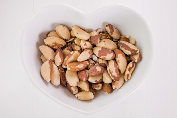 brasil nuts in white heart shape bowl