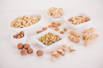 variety, mixture of different nuts on white background in white bowls 