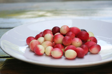 Red karonda on white plate on table background