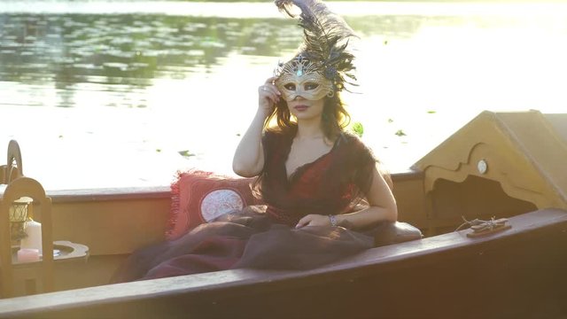 Beautiful woman with carnival mask on gondola, Venice, Italy.