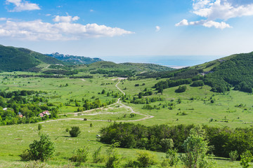 Fototapeta na wymiar A beautiful landscape view over a mountain valley and forested mountain peaks of Velebit mountain range in Croatia of the Adriatic sea or coastline with islands. Summer in Croatia or travel concept