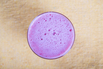 Healthy eating, food, dieting and vegetarian concept - glass of juice smoothie from strawberries. Pink strawberry shake on yellow background, close up, top view