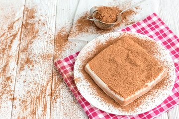 Homemade layered cottage cheese souffle dessert with cocoa on white wooden table