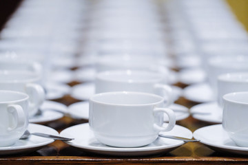 Many rows of white ceramic coffee or tea cups.