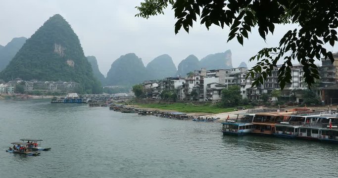 Scenic view of sailing boat along the Li River among green woods and karst mountains at Yangshuo County of Guilin, China. Yangshuo is a popular tourist destination of Asia.