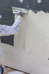 Tecnician plastering exterior wall, facade plasterers at work. movement motion blur