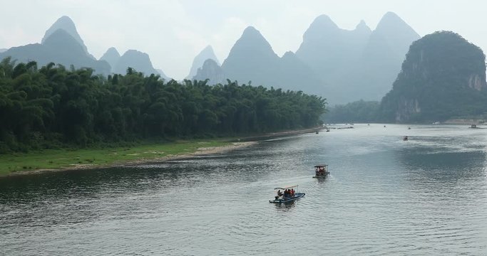 Scenic view of sailing boat along the Li River among green woods and karst mountains at Yangshuo County of Guilin, China. Yangshuo is a popular tourist destination of Asia.