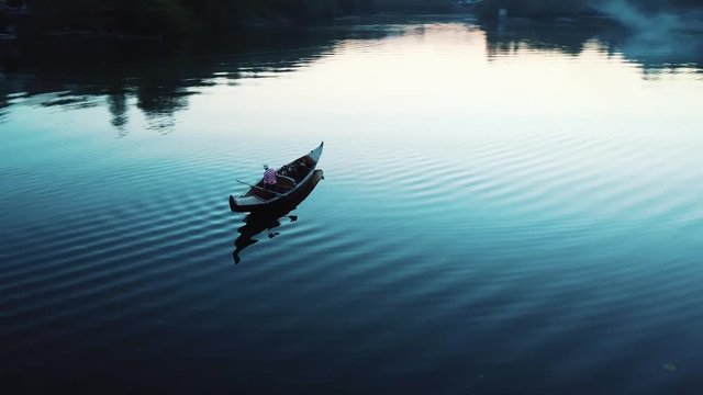Aerial view of a luxurious woman floating in a boat on a river at night. Traditional Venetian rowing boat