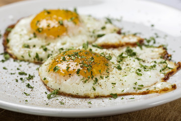 Two Fried Eggs On The White Plate With Salt and Green Parsley
